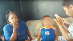 Ženy s malým chlapcem sedí na gauči a kouří marihuanu.