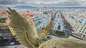 Pohled na prostor Václavského náměstí a okolí přes křídla čerstvě zrekonstruovaného sousoší „Nadšení“ od sochaře Bohuslava Schnircha z roku 2016