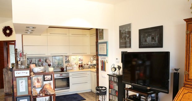 Moderní kuchyně smetanové barvy je propojena s obývacím pokojem.