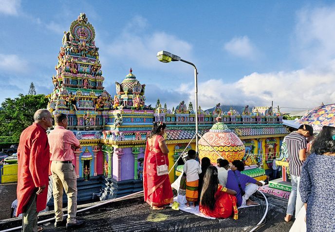 Diváci sledují chůzi po žhavém uhlí na nádvoří chrámu