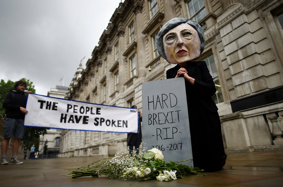 Odpůrci Mayové v masce premiérky u symbolického hrobu brexitu.