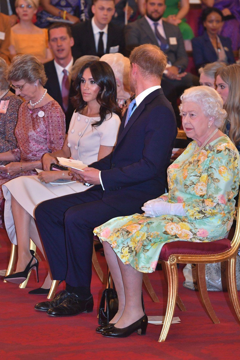Královna Alžběta s vnukem Harrym a Meghan Markle.