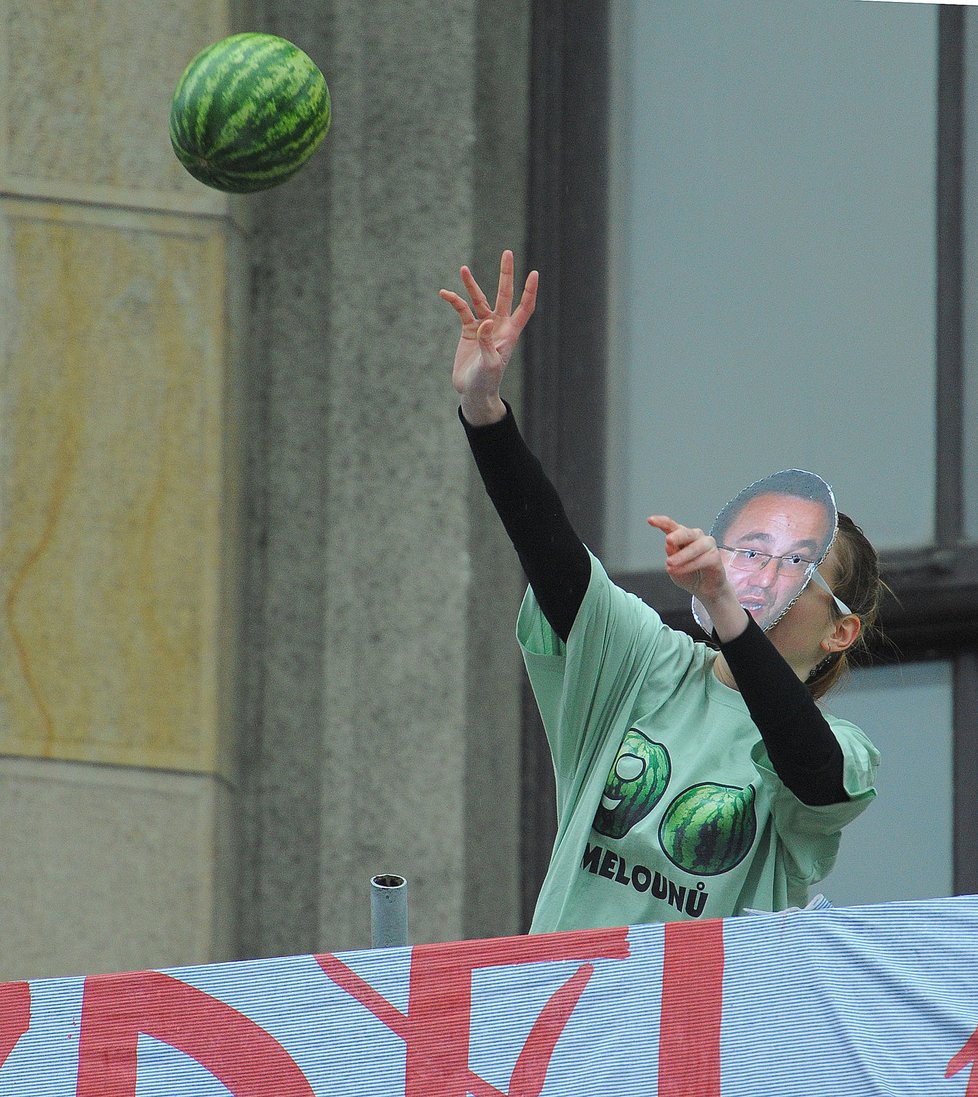 Student v masce představující ministra školství Josefa Dobeše vyhazuje z balkónu právnické fakulty jeden z melounů