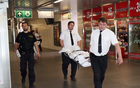 Pracovníci pohřební služby vynášejí tělo sebevraha z metra