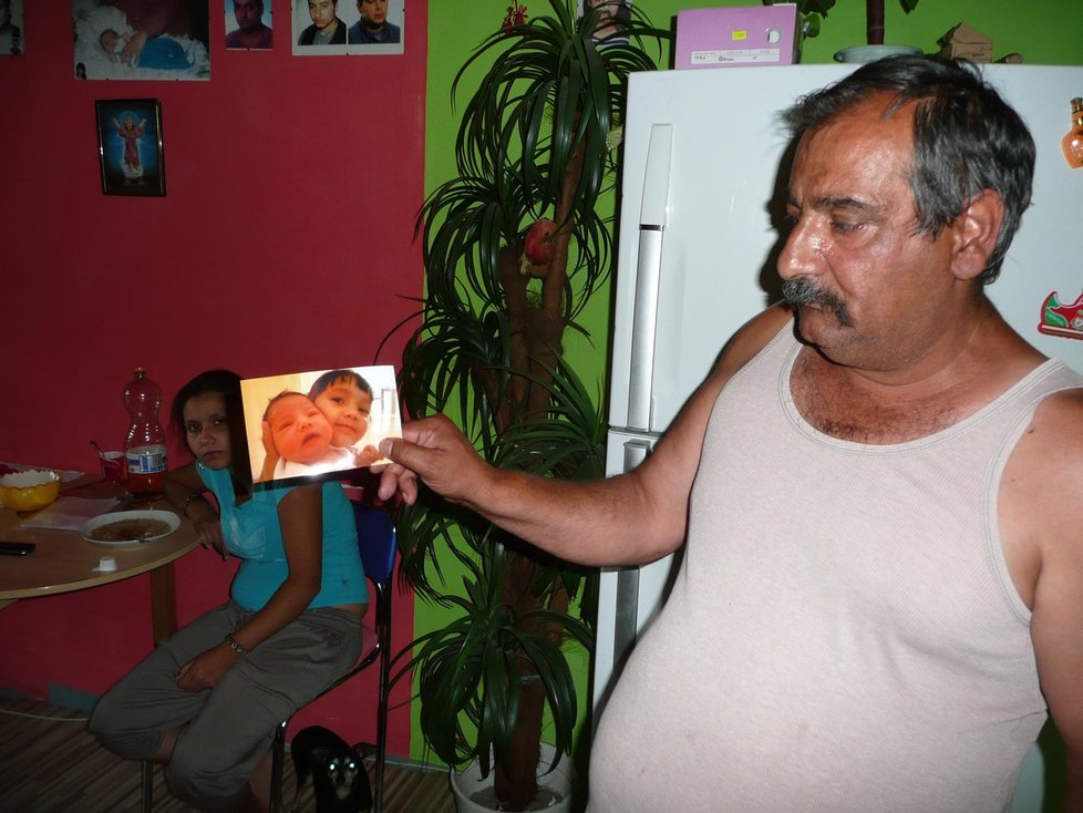 Dědeček Michalky ukazuje její foto, v pozadí sedí její matka
