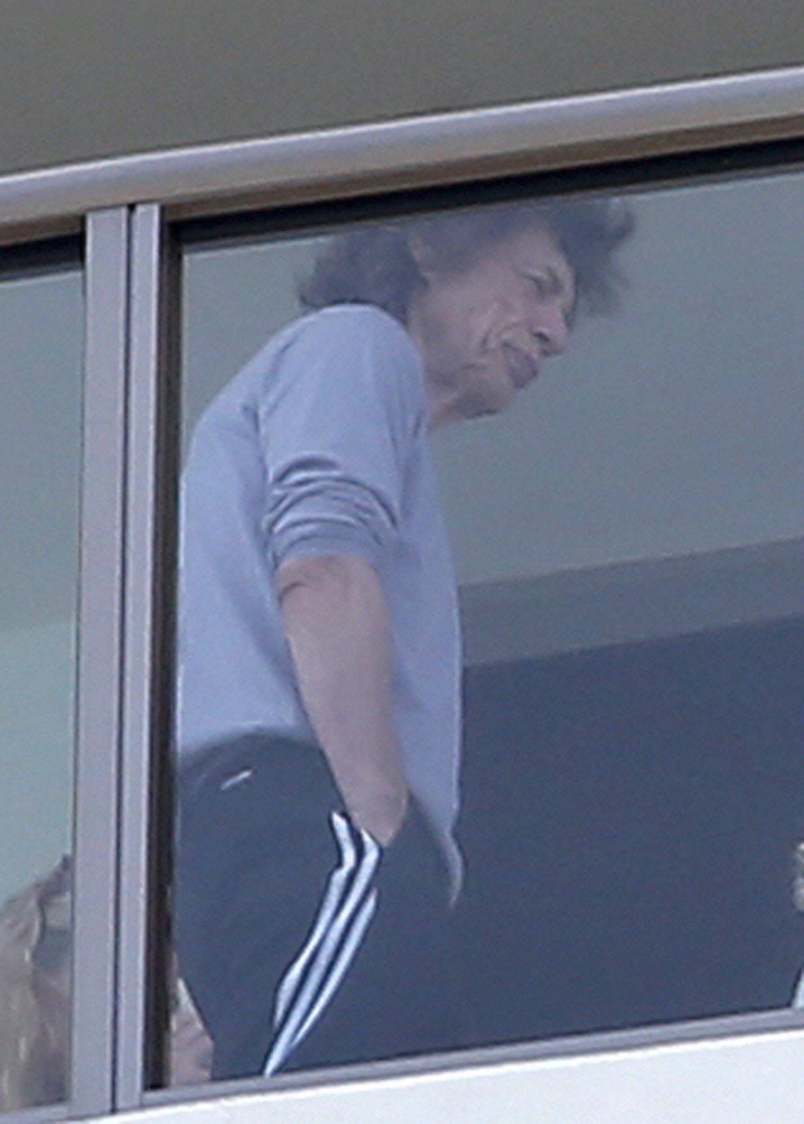 Nemocný Mick Jagger v teplákách na balkoně. 