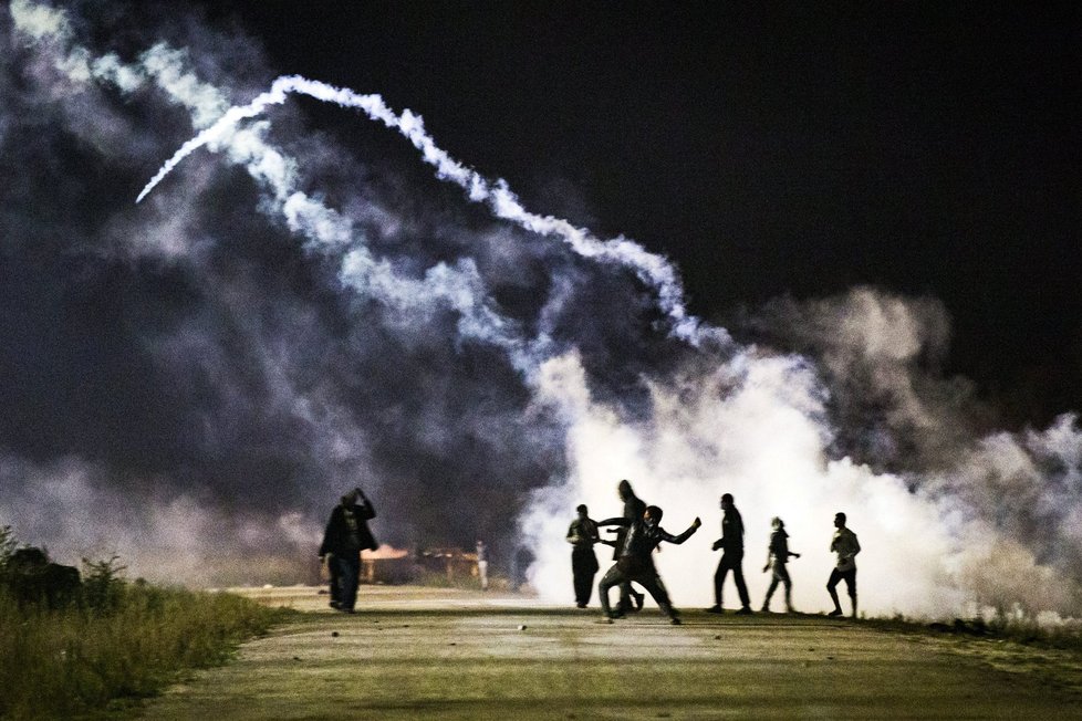 Utečenci měli na policii házet lahve a kamení, ta odpovídala kouřovými granáty. Tábor v Calais má být od pondělí bourán.