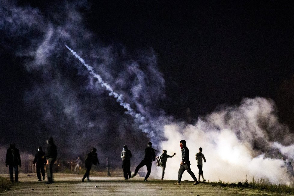 Utečenci měli na policii házet lahve a kamení, ta odpovídala kouřovými granáty. Tábor v Calais má být od pondělí bourán.