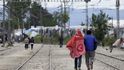 Uprchlíci kráčejí po kolejích u Idomeni