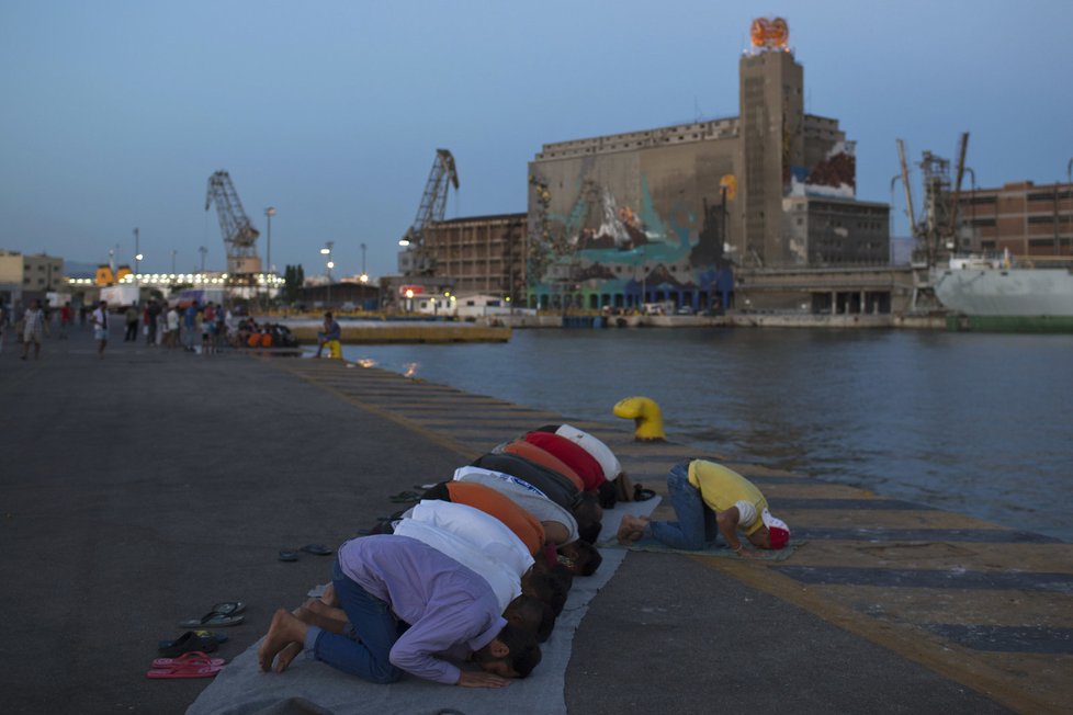Migranti z Afghánistánu se modlí v řeckém přístavu Pireus.