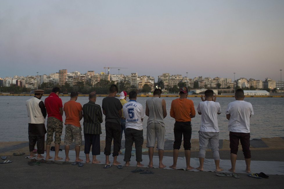 Migranti z Afghánistánu se modlí v řeckém přístavu Pireus.