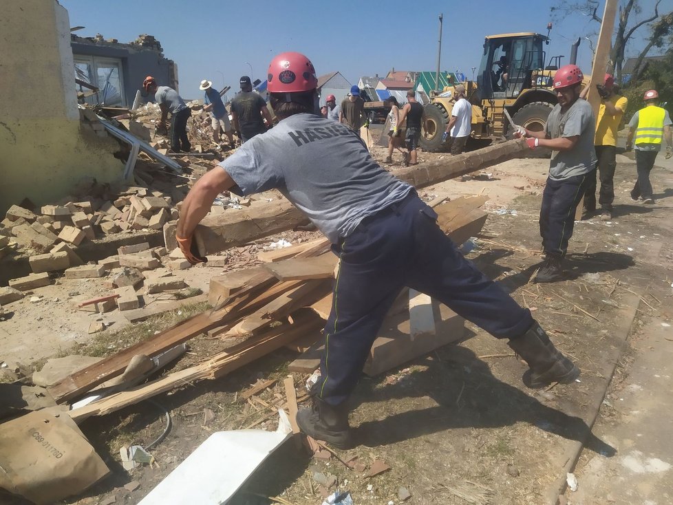 Hasiči a dobrovolníci odnášeli materiál z místa, kde padl první mikulčický dům poškozený tornádem.