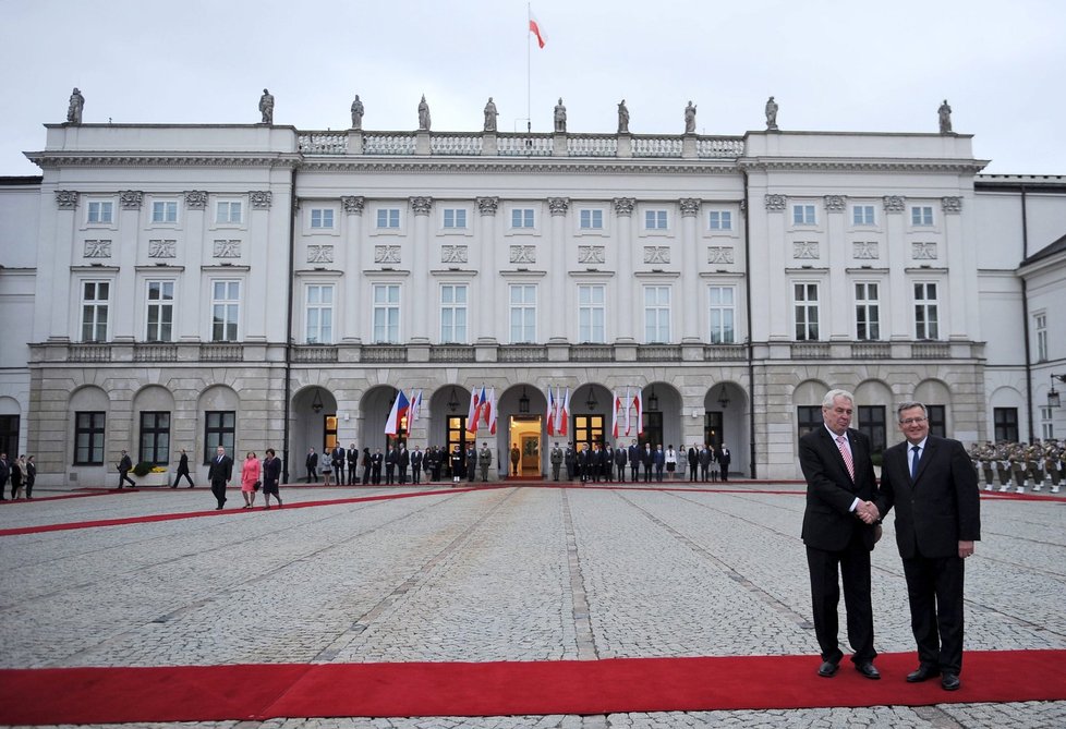 Miloš Zeman a Bronislaw Komorowski si potřásají rukou, po červeném koberci přichází první dámy