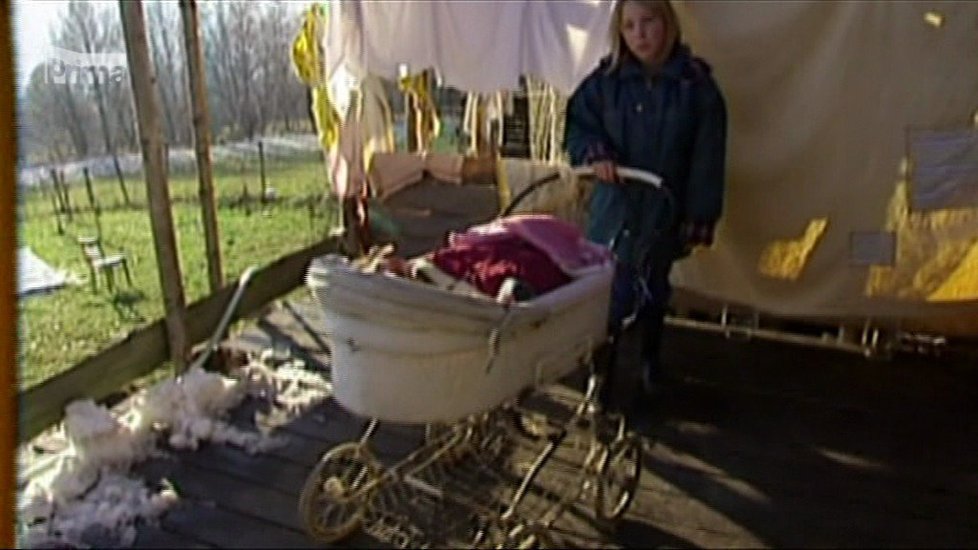 Matka houpe dítě v kočárku.