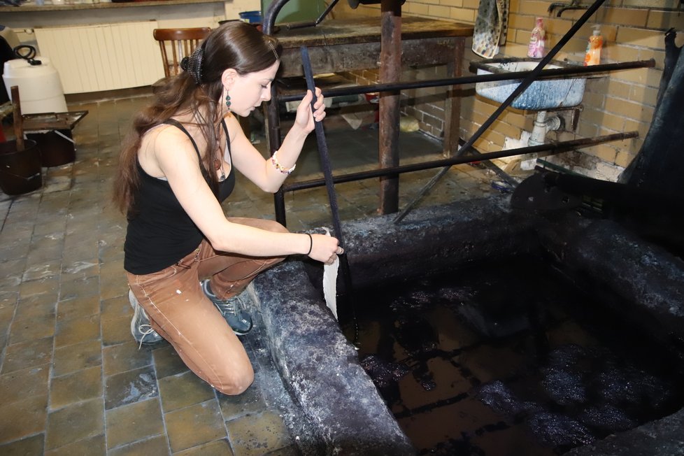 Gabriela Bartošková (27) ponořuje látku do indiga. Jáma je hluboká dva metry.
