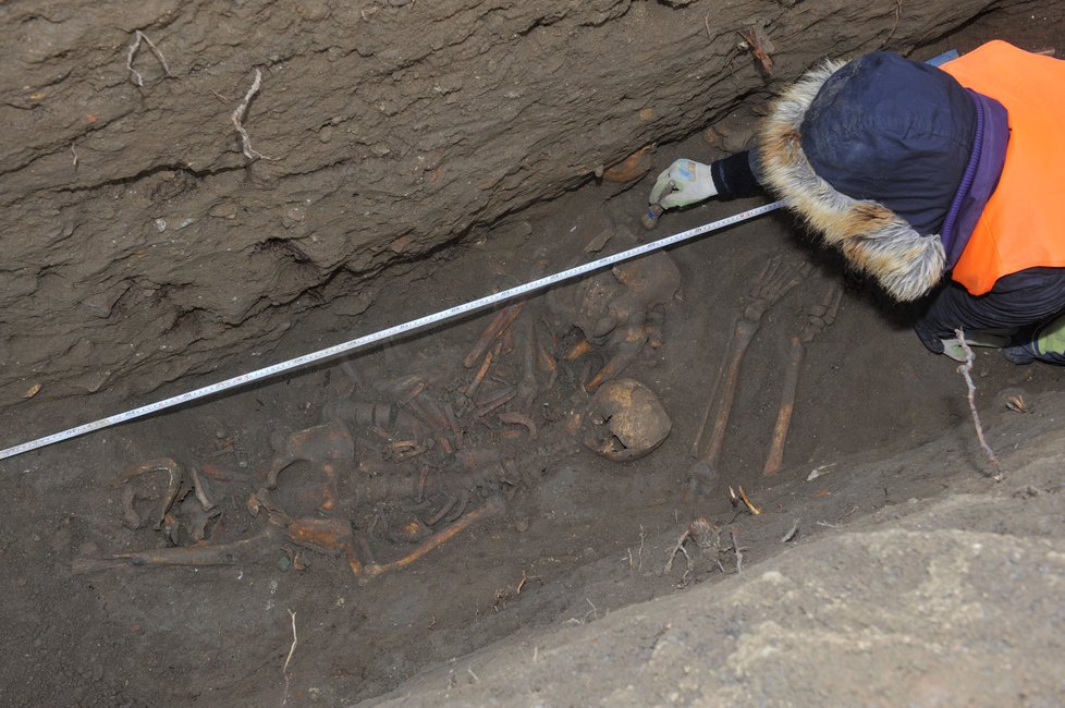 Archeolog pracuje v hrobě s ostatky tří osob