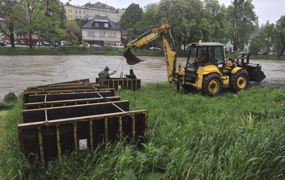 Dělníci uklízejí stavební materiál ze břehu rozvodněné řeky Olše
