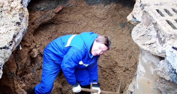 Pracovník Brněnských vodáren a kanalizací odkopává krumpáčem zeminu u prasklého potrubí v Rolnické ulici na sídlišti v Brně-Bohunicích.