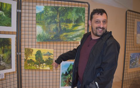 Milan Tóth ukazuje na krajinu, kterou maloval už levačkou.