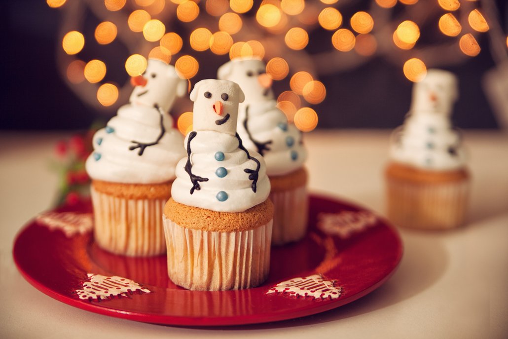 Sladké muffiny zdobené krémem ve tvaru sněhuláků