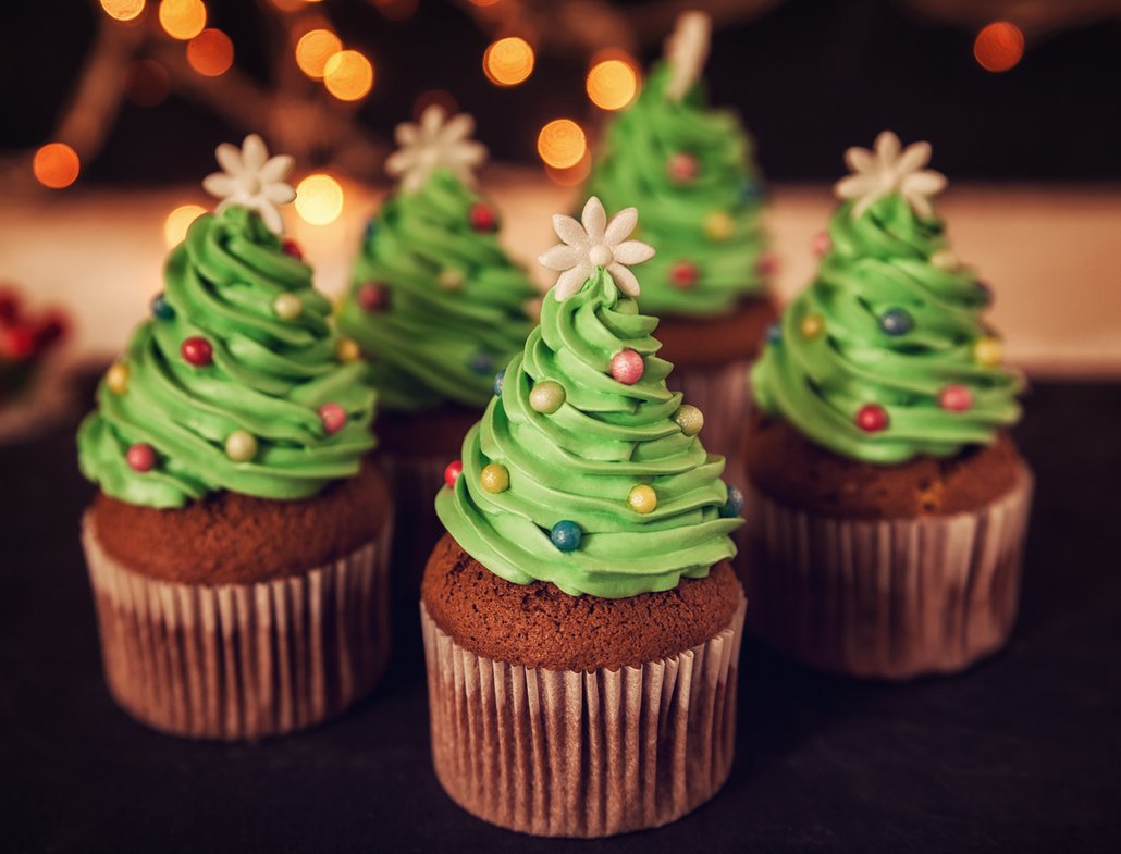 Sladké muffiny zdobené zeleným krémem ve tvaru stromečků