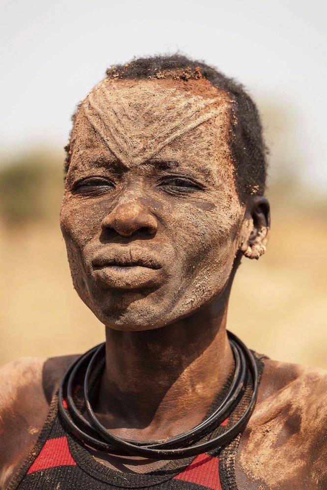 Každé ráno začíná u tohoto afrického kmene stejně. Vybraný mladík vstane, zběžně si vyčistí zuby klacíkem a pak si &#34;umyje&#34; hlavu pod nedaleko močící krávou. Improvizovaná sprcha má antibakteriální účinky a navíc mu zbarví vlasy do tradičních oranžových barev Mundariů. 