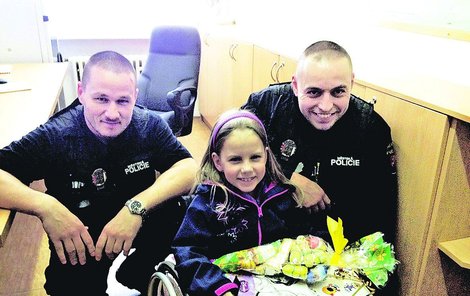 Strážníci Konstantin Mazare a Jiří Gold (zleva) s postiženou Karolínkou, které přispívají na její léčbu.