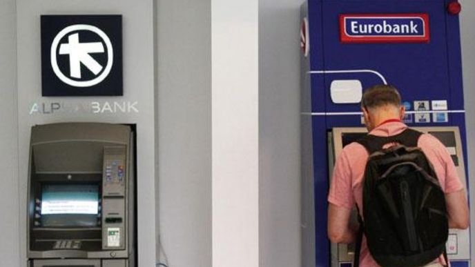 Muž v Aténách vybírá peníze z bankomatu
Eurobank ATM vedle téhož
zařízení společnosti Alpha
Bank.