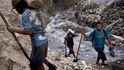 Muži vybavení lopatami se s pytli plnými nasbíraného kovového odpadu brodí kontaminovanými vodami protékajícími dnem jedné z největších guatemalských skládek zvané "důl".