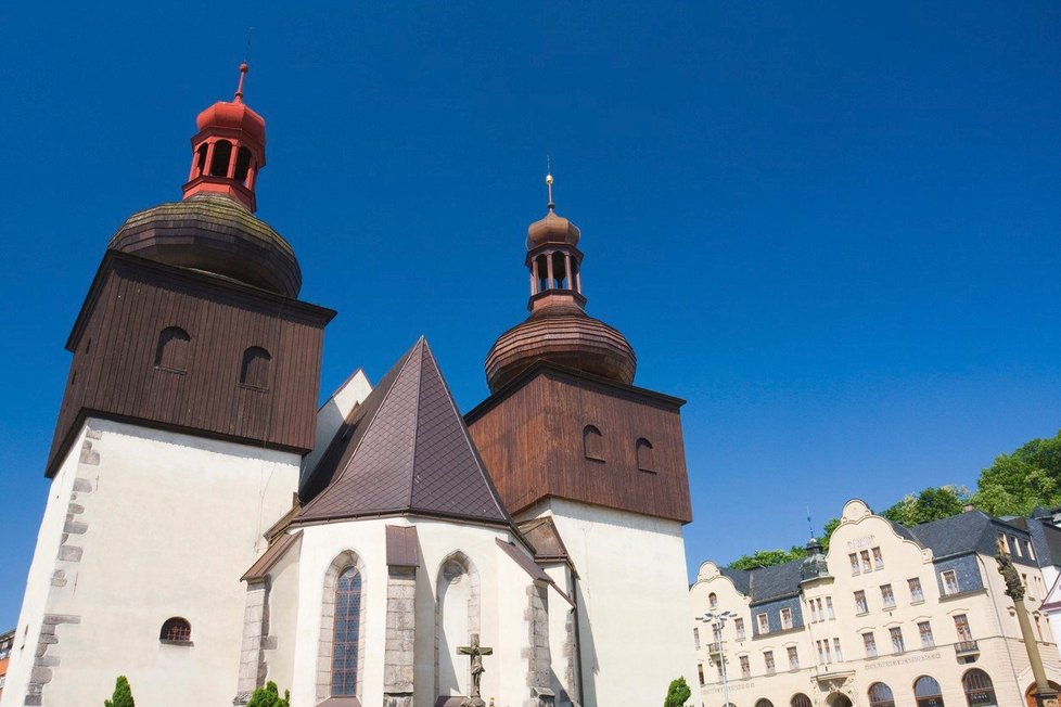 Na náměstí v Náchodě si všimněte věží kostela, které mají nahoře dřevěné bednění a báně.