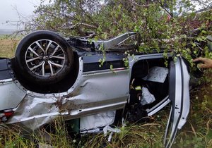 Řidič dostal na dálnici D5 smyk, vůz skončil v poli na střeše.