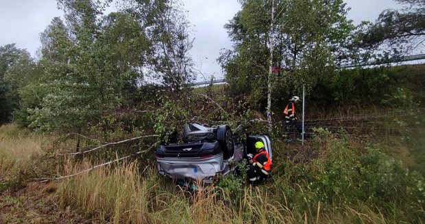 Řidič dostal na dálnici D5 smyk, vůz skončil v poli na střeše.