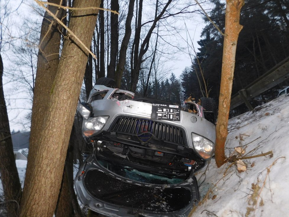 Co dokáže kluzká silnice? Auto na střeše uvízlo mezi stromy, řidič z něj vylezl nezraněný