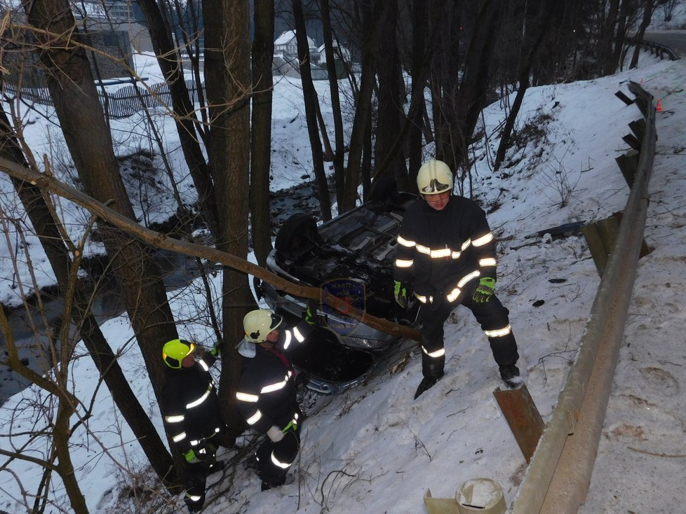 Auto obrácené na střechu uvízlo mezi stromy, řidič z něj vylezl nezraněný.