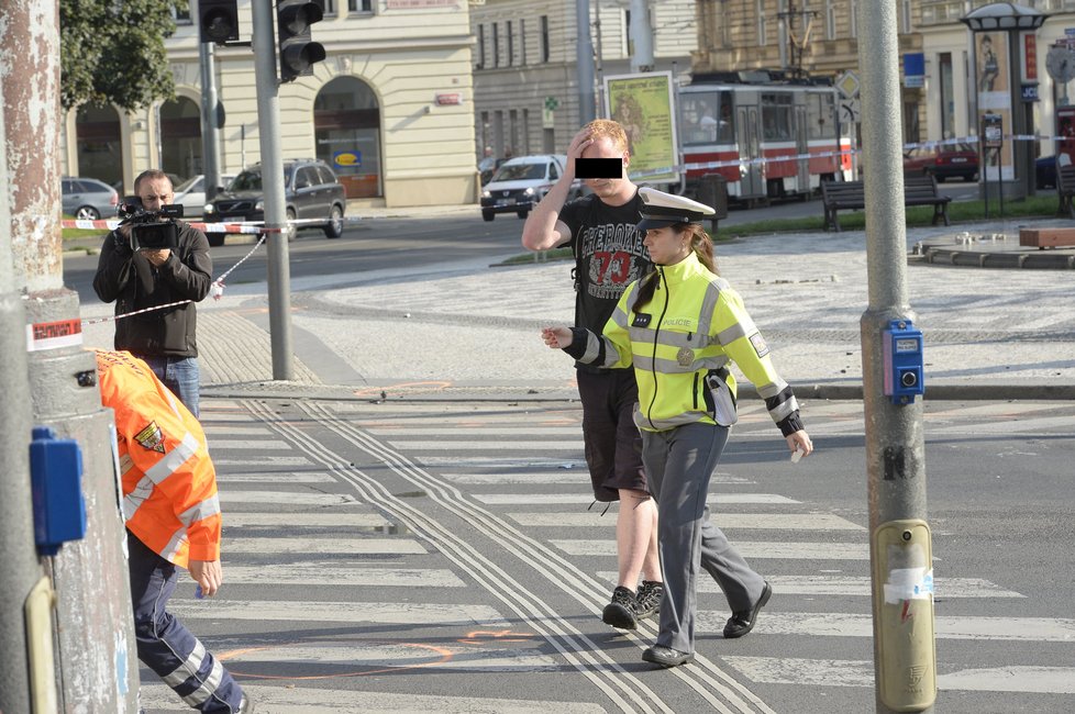 Policistka odvádí mladíka do sanitky