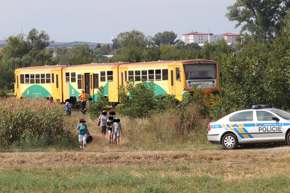 Záchranáři vyvádějí cestující z havarovaného vlaku.