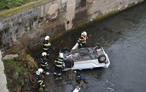 Auto prorazilo zábradlí na mostě a dopadlo do řeky na střechu.