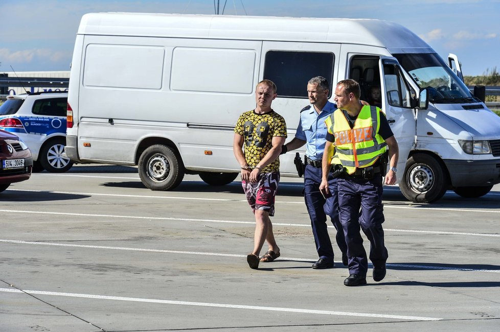 Němečtí policisté odvádějí jednoho z řidičů v poutech. Pravděpodobně u něj našli kontraband.