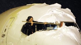 Personál letiště se snaží zbavit letadla nánosů sněhu