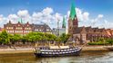 Historické město Brémy se starou plachetnicí na řece Weser.