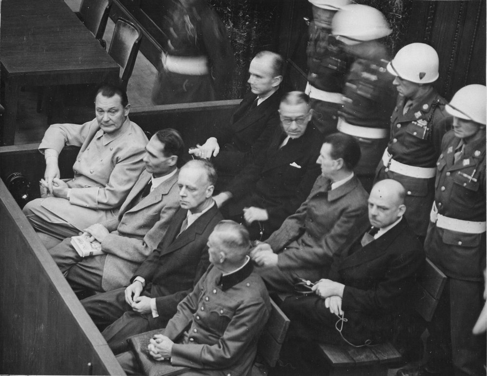 Lavice obžalovaných - zleva: Göring, Hess, von Ribbentrop a Keitel. Druhá řada: Dönitz, Raeder, Schirach a Sauckel