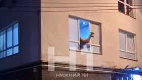 Spoře oděná prostitutka visící z okna v Novgorodu