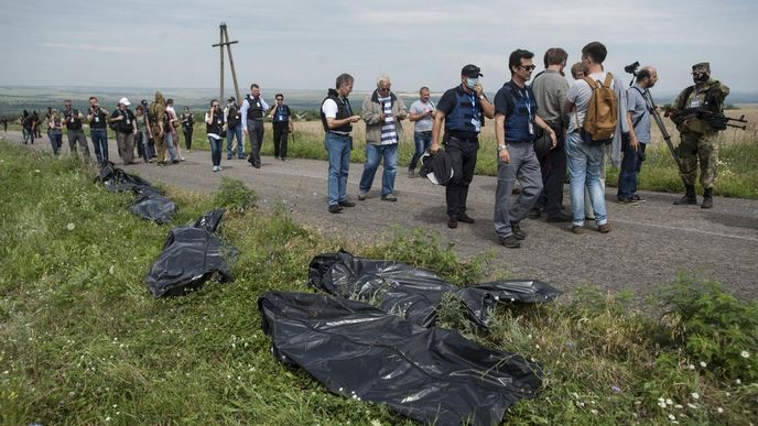 Novináři jdou kolem mrtvých těl obětí ze sestřeleného malajsijského letadla poblíž obce Hrabove na východě Ukrajiny