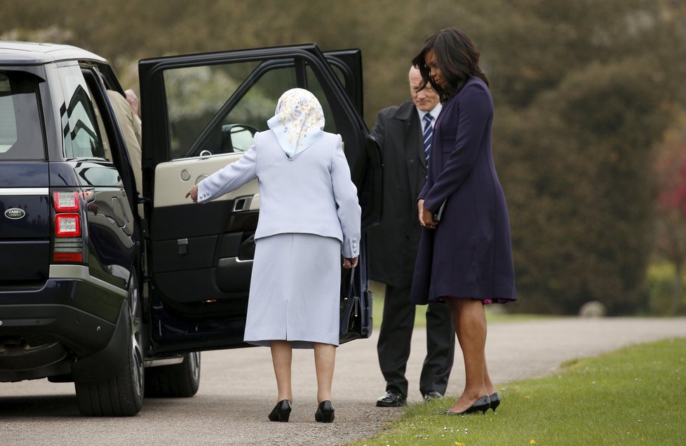Královna Alžběta II. ukazuje Michelle Obamové, kam se má posadit.