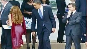 Barack Obama a Nicolas Sarkozy si zálibně prohlížejí pozadí ženy, která se s nimi jde fotit
