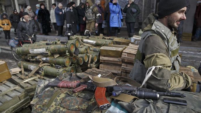 Obyvatelé Debalceve stojí ve frontě na humanitární pomoc, ozbrojený separatista střeží zbraně a střelivo