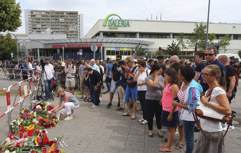 Lidé pokládají květiny před obchodní centrum Olympia.