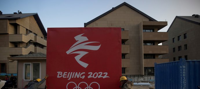 Čínští dělníci upevňují ceduli v olympijské vesnici