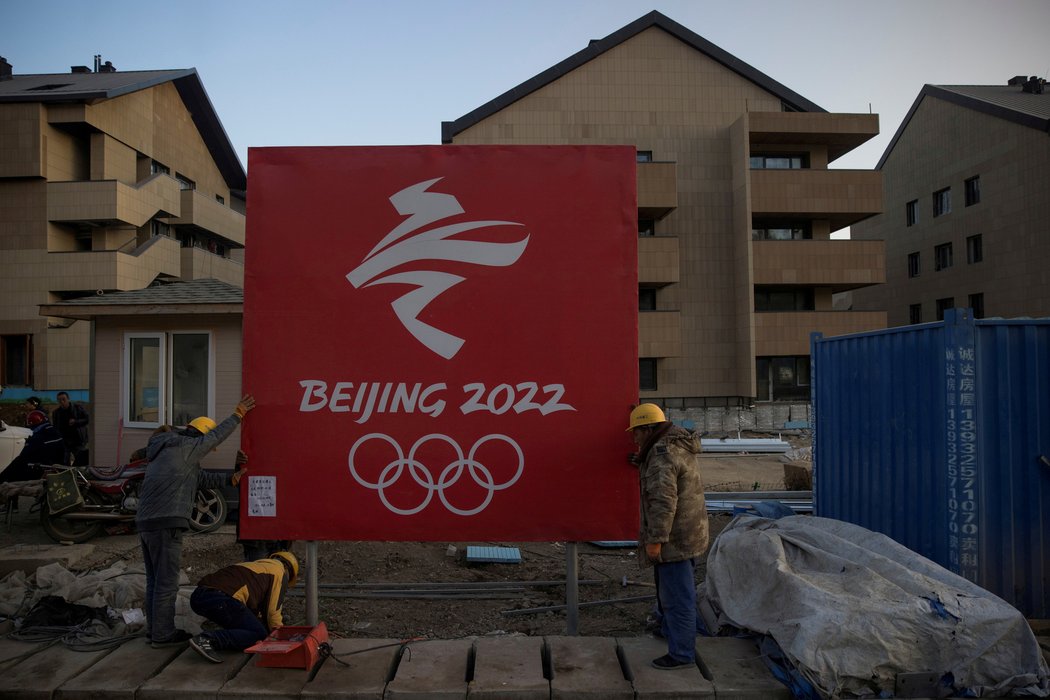 Čínští dělníci upevňují ceduli v olympijské vesnici
