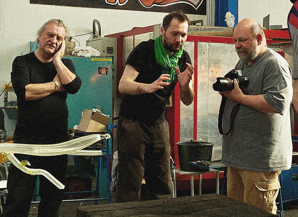 Bořek Šípek a Ondřej Smeykal ve sklárně A je to dohlížejí na výrobu skleněných didgeridoo